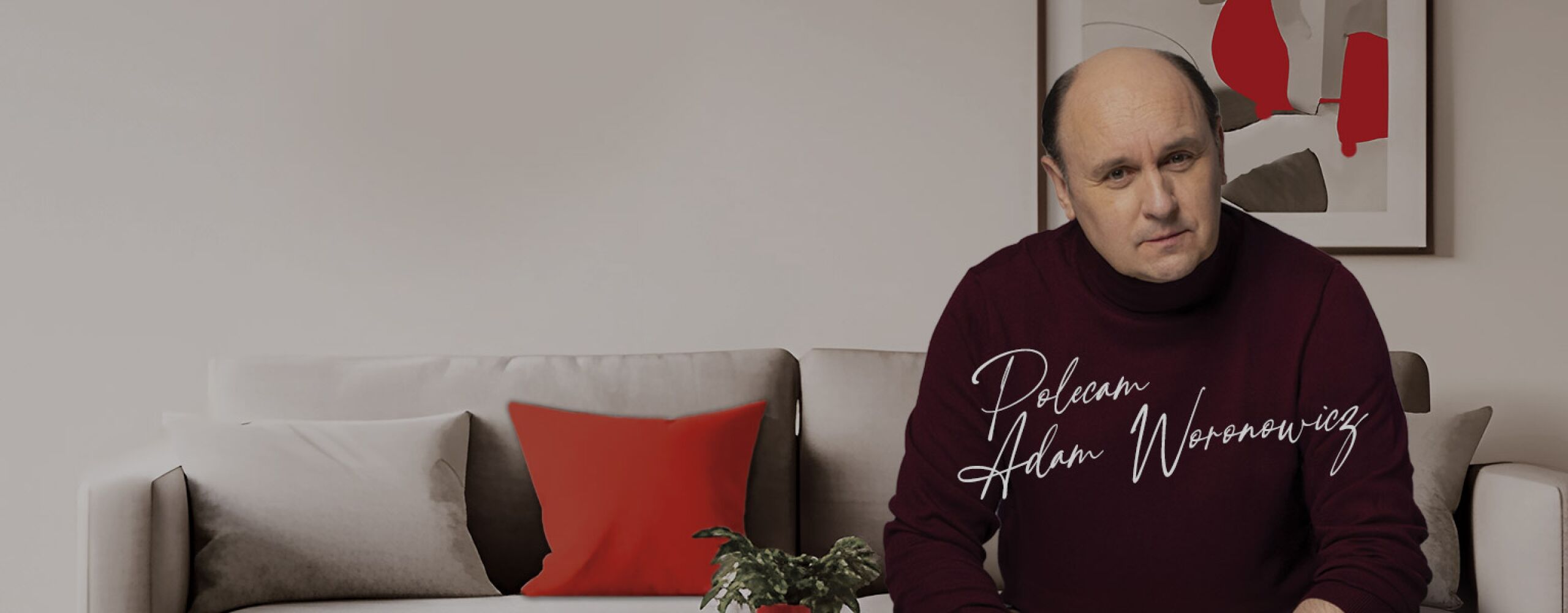 aktor Adam Woronowicz siedzący na kanapie