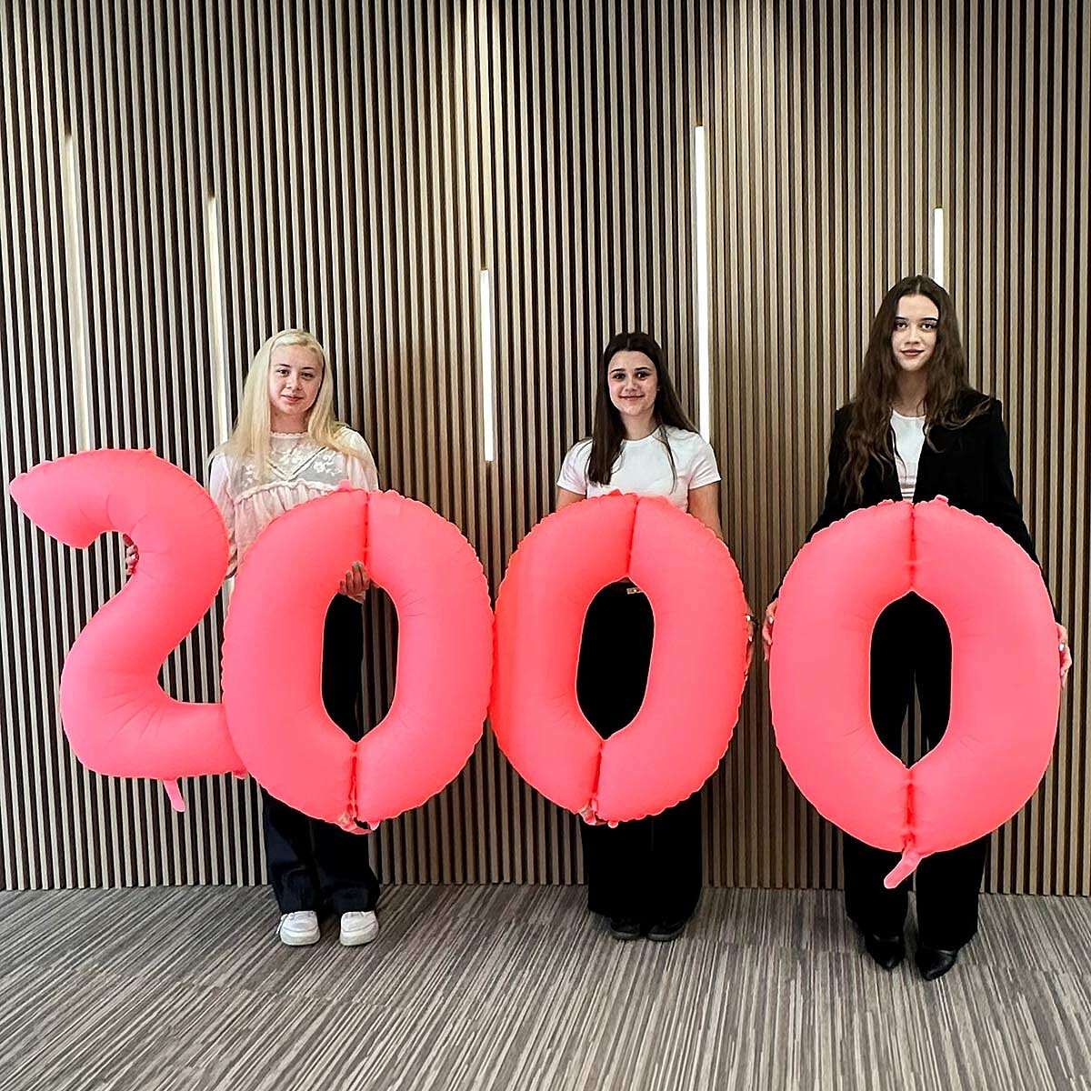 Trzy młode dziewczyny trzymające balony z liczbą 2000