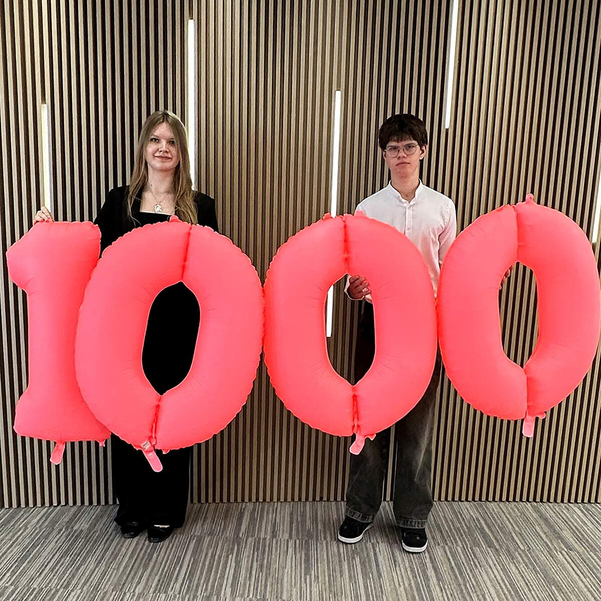 Chłopak i dziewczyna trzymający balony z liczbą 1000